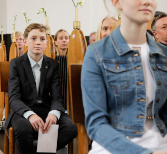 En konfirmand på sin særlige plads ved midtergangen i kirken under konfirmationen.