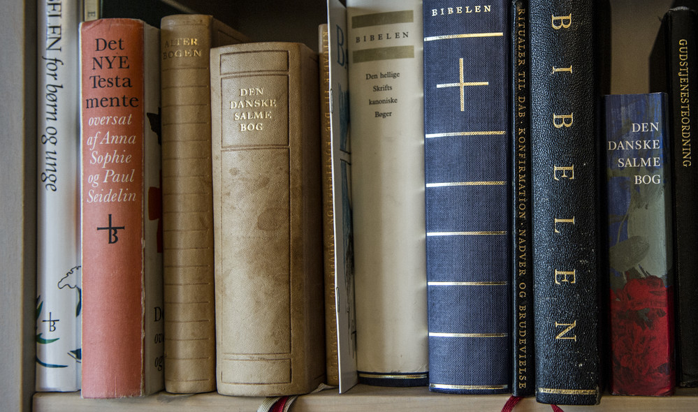Reol med bibler i forskellige udgaver. Ny Testamente er en samling af de fire evangelier om Jesus og breve og beretninger fra de tidligste kristne menigheder