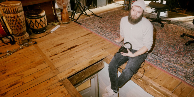 Musiker Thomas Alstrup sidder på gulvet i sit studie med høretelefoner i skødet