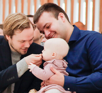 Faddere sidder i kirken med deres fadderbarn til barnedåb