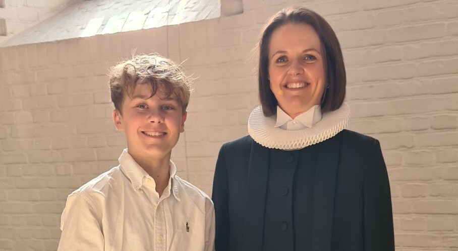 Bjørn står ved siden af præsten, efter han blev døbt op til sin konfirmation