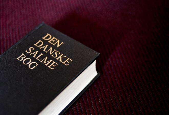 Den danske salmebog på bordeaux baggrund.