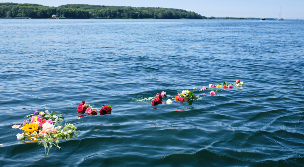 Blomsterbuketter flyder i havoverfladen efter en askespredning.