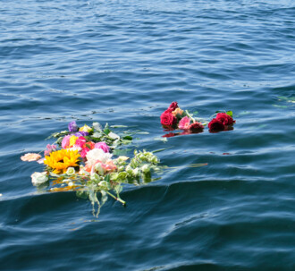 Blomsterbuketter flyder i havoverfladen efter en askespredning.