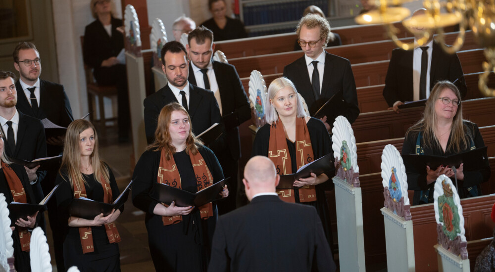 Aalborg Domkirkes Kantori står på kirkegulvet mellem kirkebænke