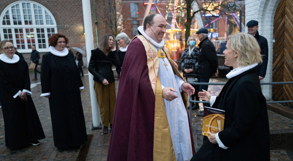Biskop Thomas Reinholdt Rasmussen smiler og hilser på præst udenfor kirke