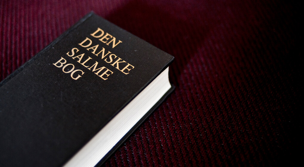 Den danske salmebog på bordeaux baggrund.